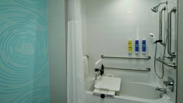 Un baño moderno con ducha a ras de suelo, barras de apoyo y un lavamanos blanco.