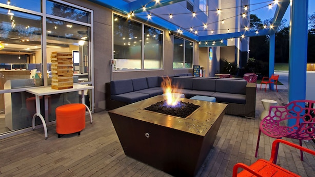 An outdoor seating area with a fire pit, cushioned seating, and string lights.