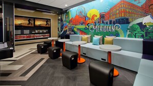 A modern lounge area with a mural, seating, and a reception desk.