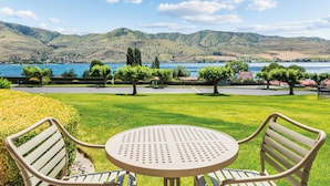 A round table with two chairs in a grassy area with a view of a lake and hills. - WorldMark Lake Chelan Shores (Chelan)