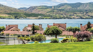 A lakeside view with a swimming pool, a tennis court, and a row of houses with red roofs. - WorldMark Lake Chelan Shores (Chelan)