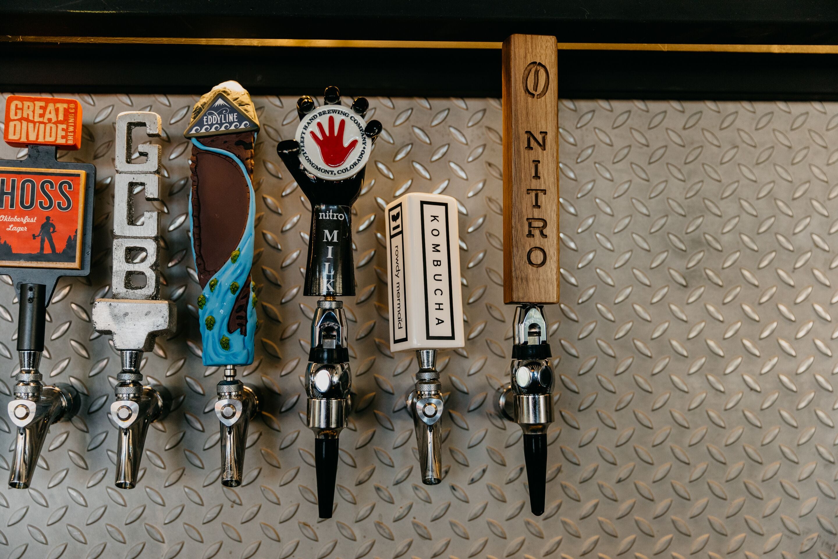 Una fila de grifos de cerveza con etiquetas como 'Eddyline', 'Kombucha' y 'Nitro'.