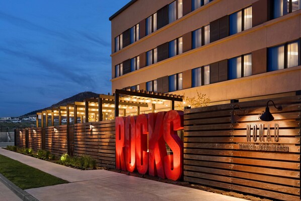 A modern building with a large illuminated sign reading "ROCKS" and a smaller sign below stating "FASHIONABLE FOGGARDEN". - Origin Red Rocks, a Wyndham Hotel (Golden)