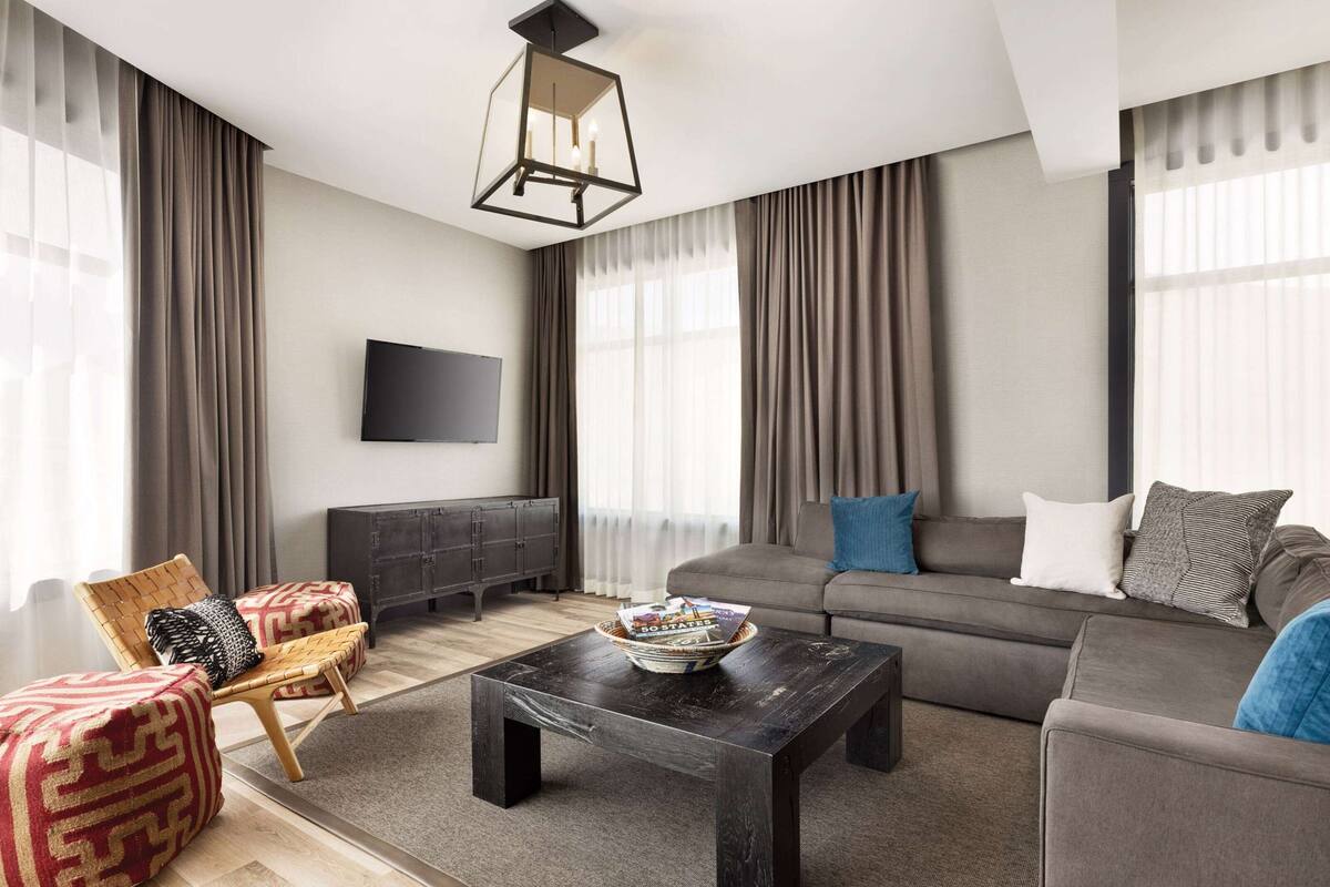 A modern living room with a sofa, a coffee table, a TV, and a fireplace.