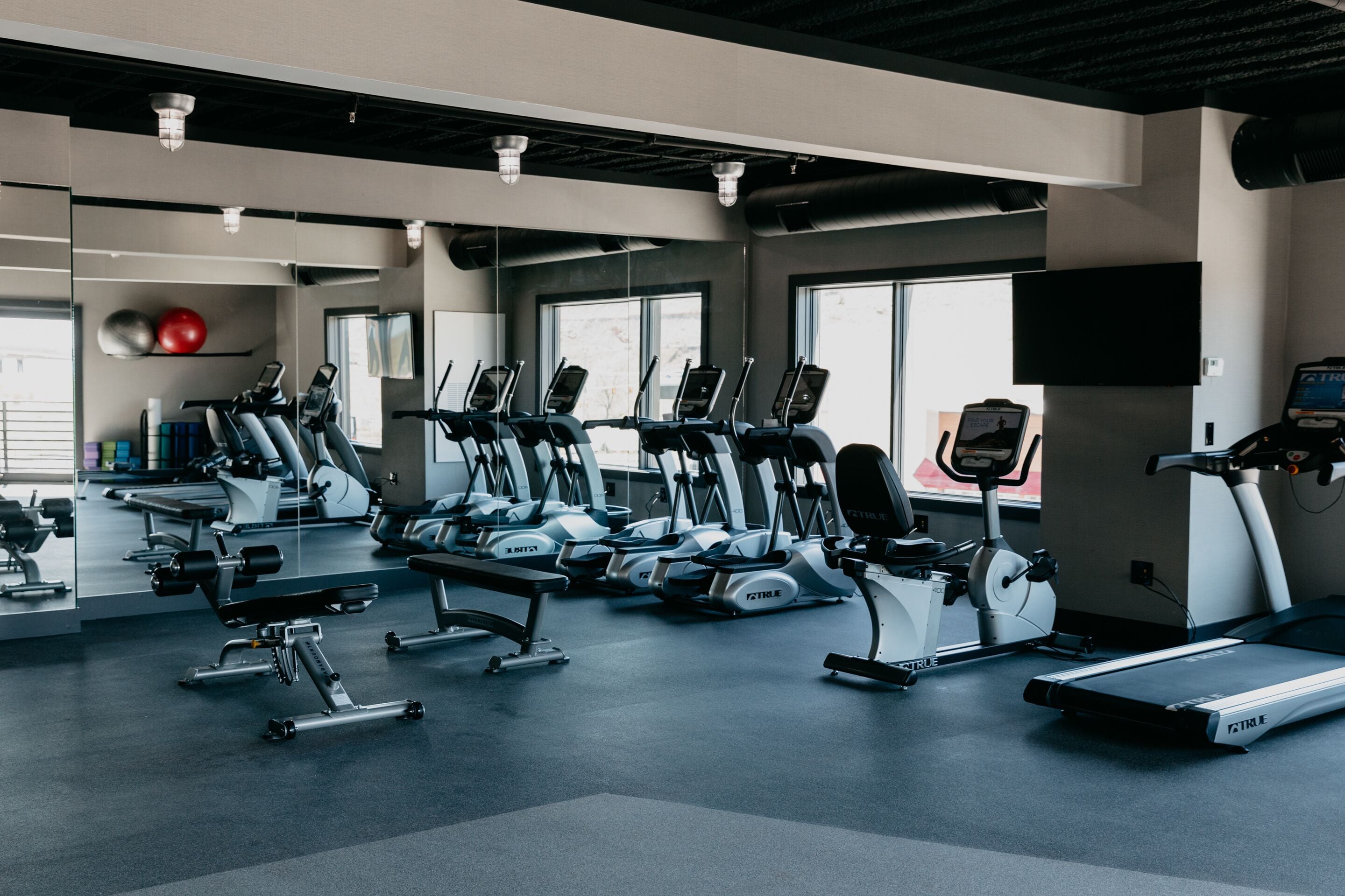Een fitnessruimte met meerdere loopbanden, elliptische trainers en een zone voor bankdrukken.