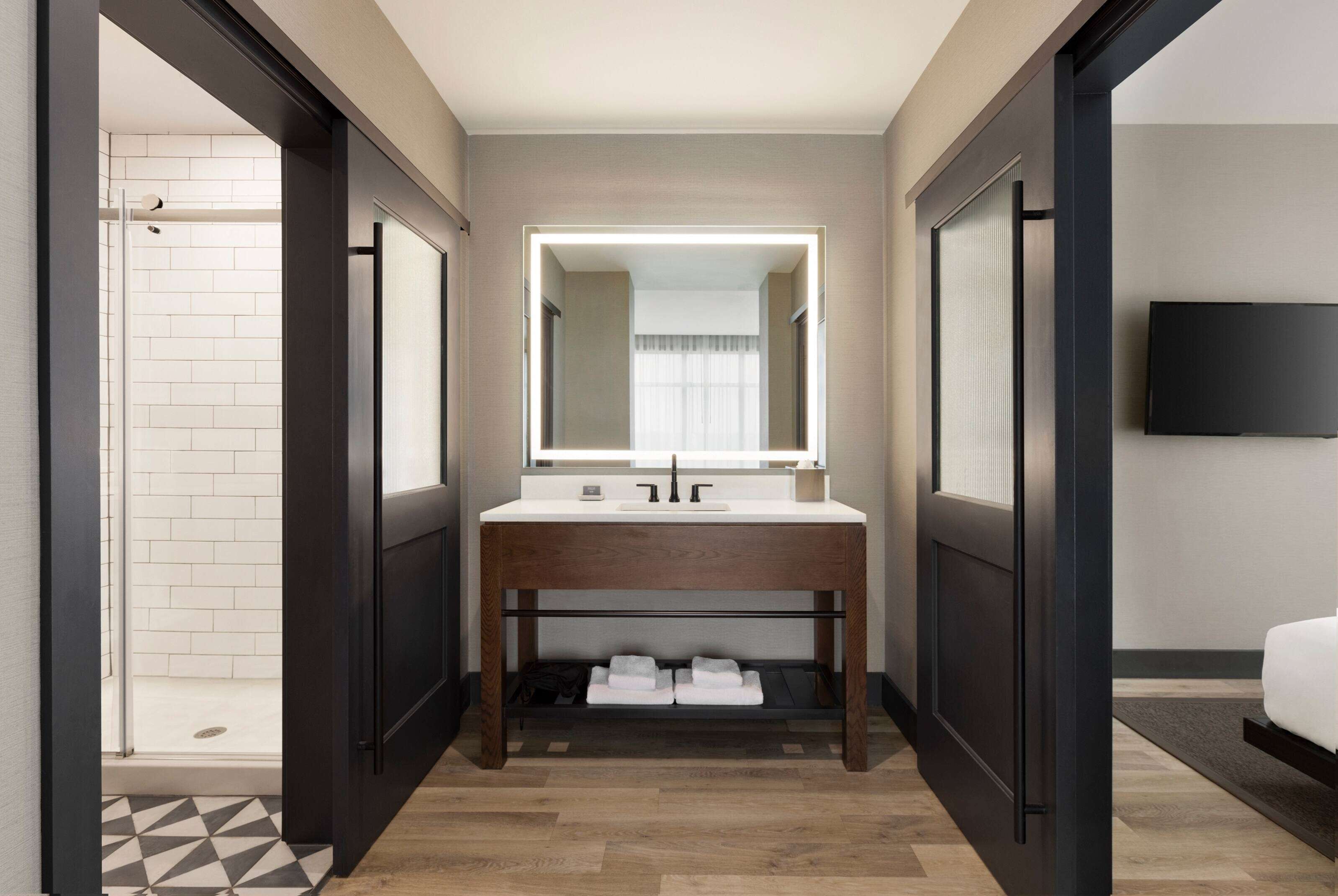A modern bathroom with a large mirror, a sink, and a shower area.