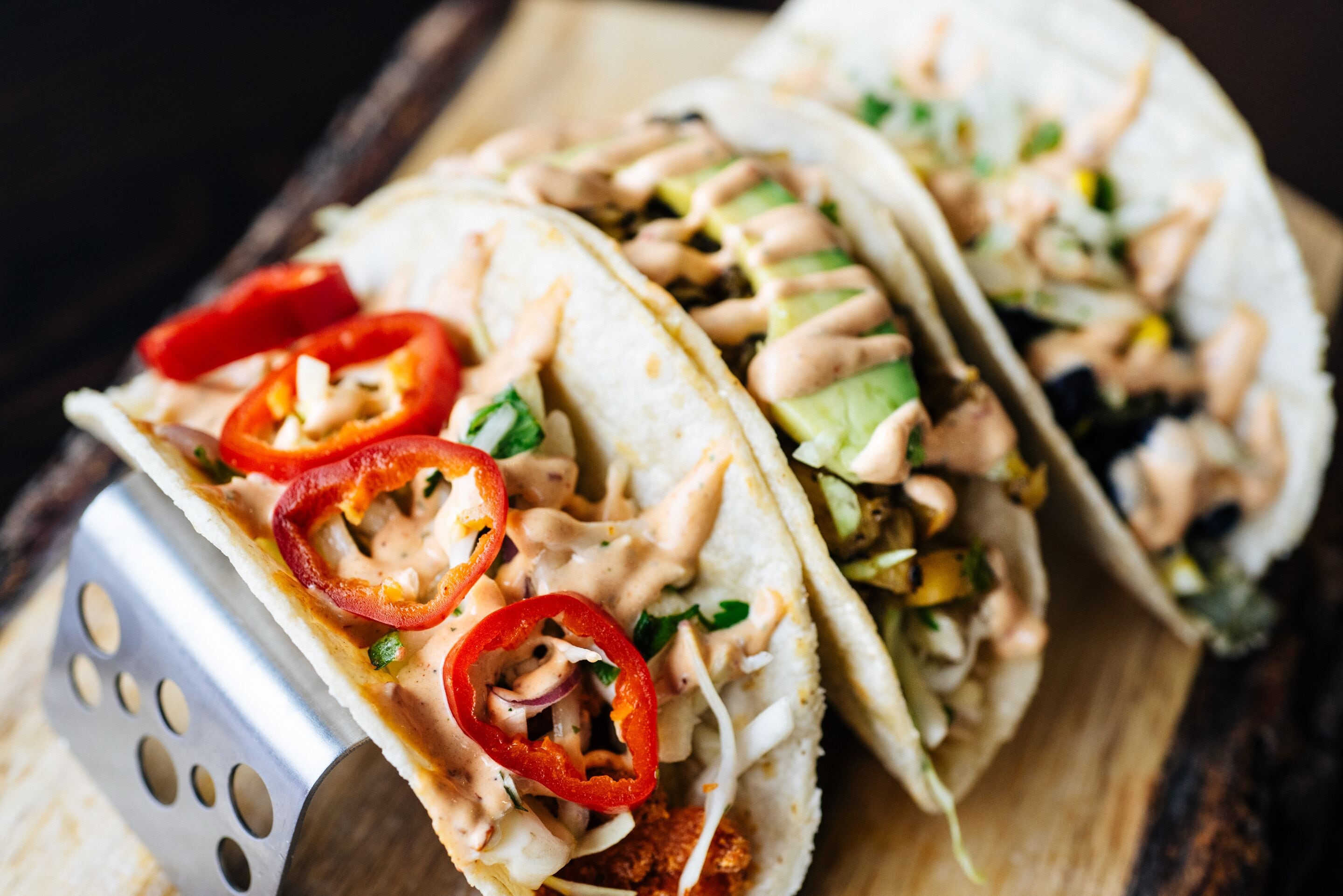 Two tacos on a wooden board with a metal spatula.