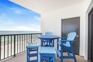 A balcony with a view of the beach and ocean, featuring blue Adirondack chairs and a small table. - Breathtaking Views, Views, Views! Oceanfront wraparound balcony; 3 BR and 3 BA. (Orange Beach)