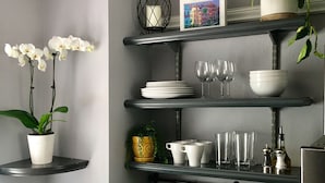 A modern kitchen with a granite countertop, stainless steel sink, and various kitchen items. - Suites on Cannon (Charleston)