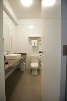 A compact bathroom with a white sink, a toilet, and a towel rack.
