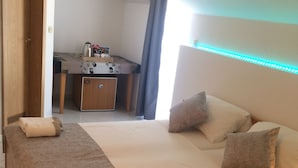 Ett hotellrum med en säng, sängbord, ett skrivbord och ett litet pentry.
