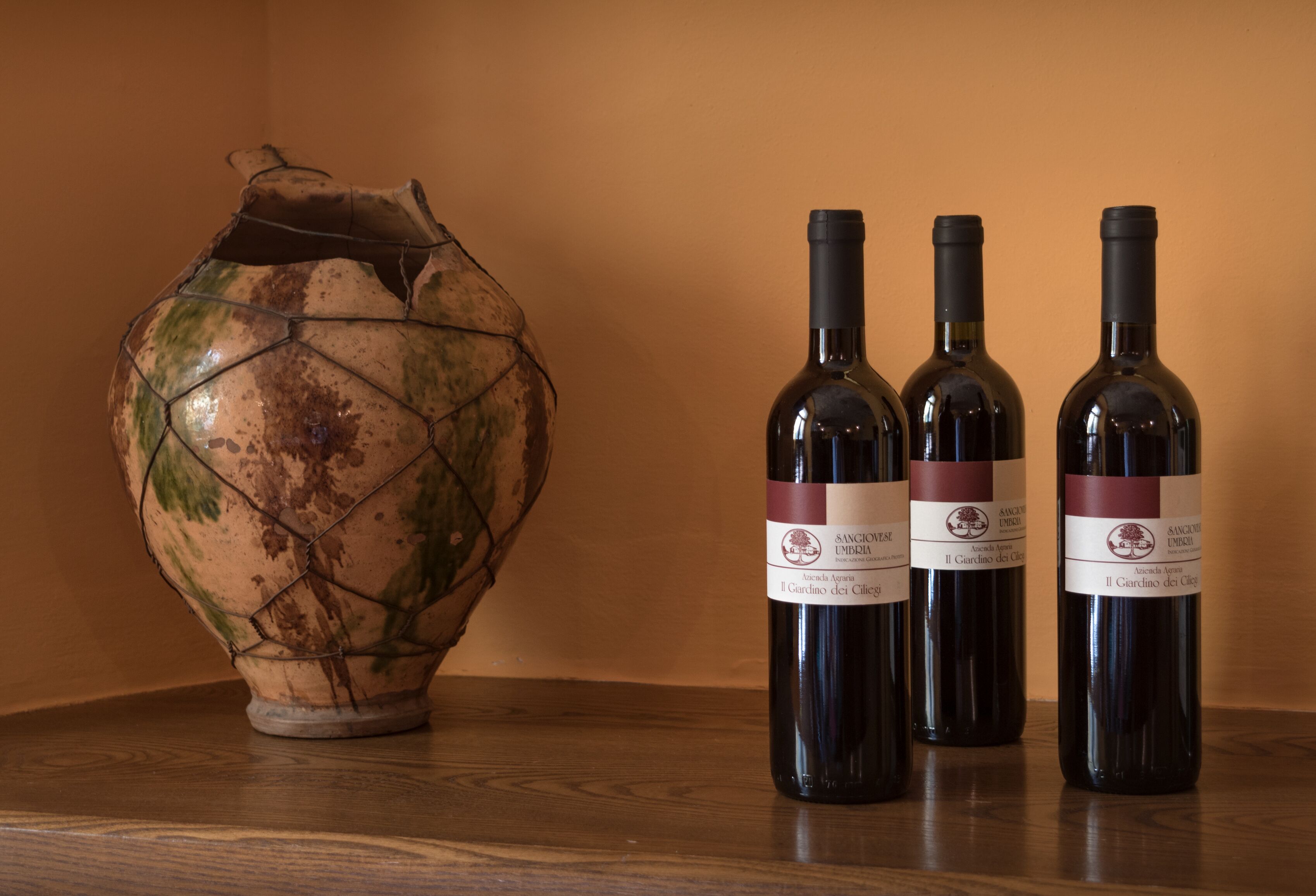 Trois bouteilles de vin et un vase en céramique sur une surface en bois.