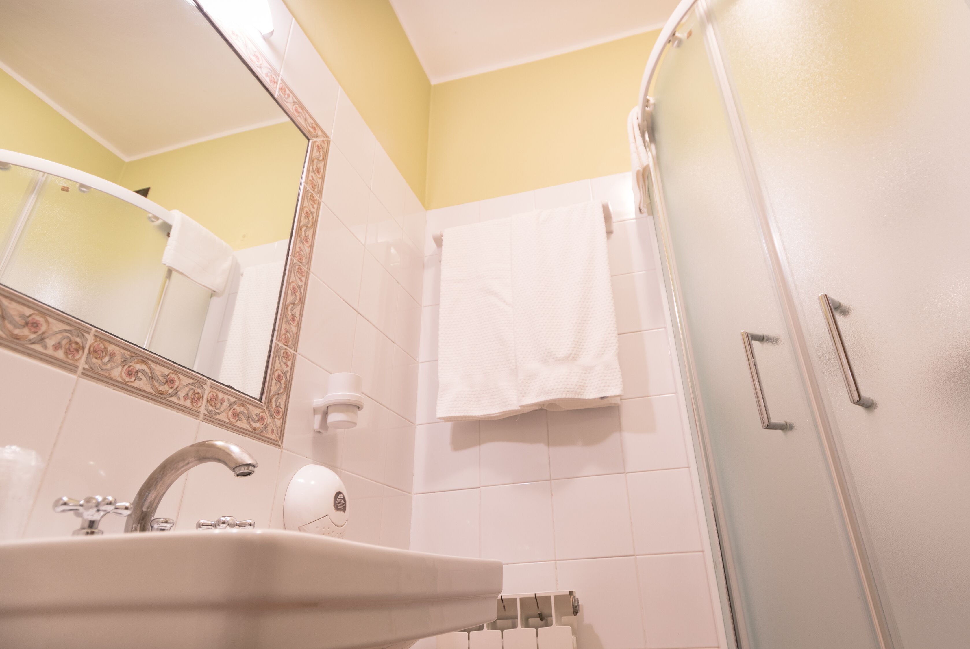 Un baño con lavamanos, espejo y ducha.