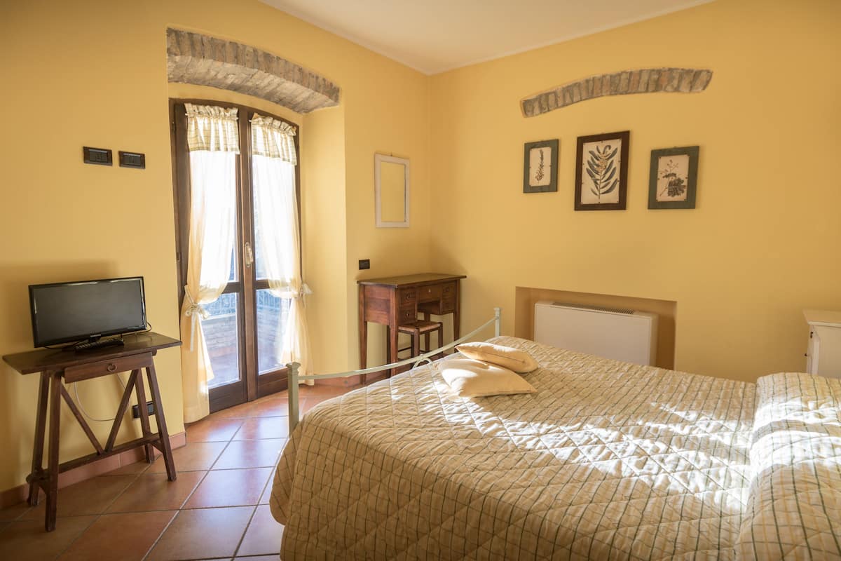 Une chambre d’hôtel avec un lit, un bureau, une télévision et une fenêtre avec des rideaux.