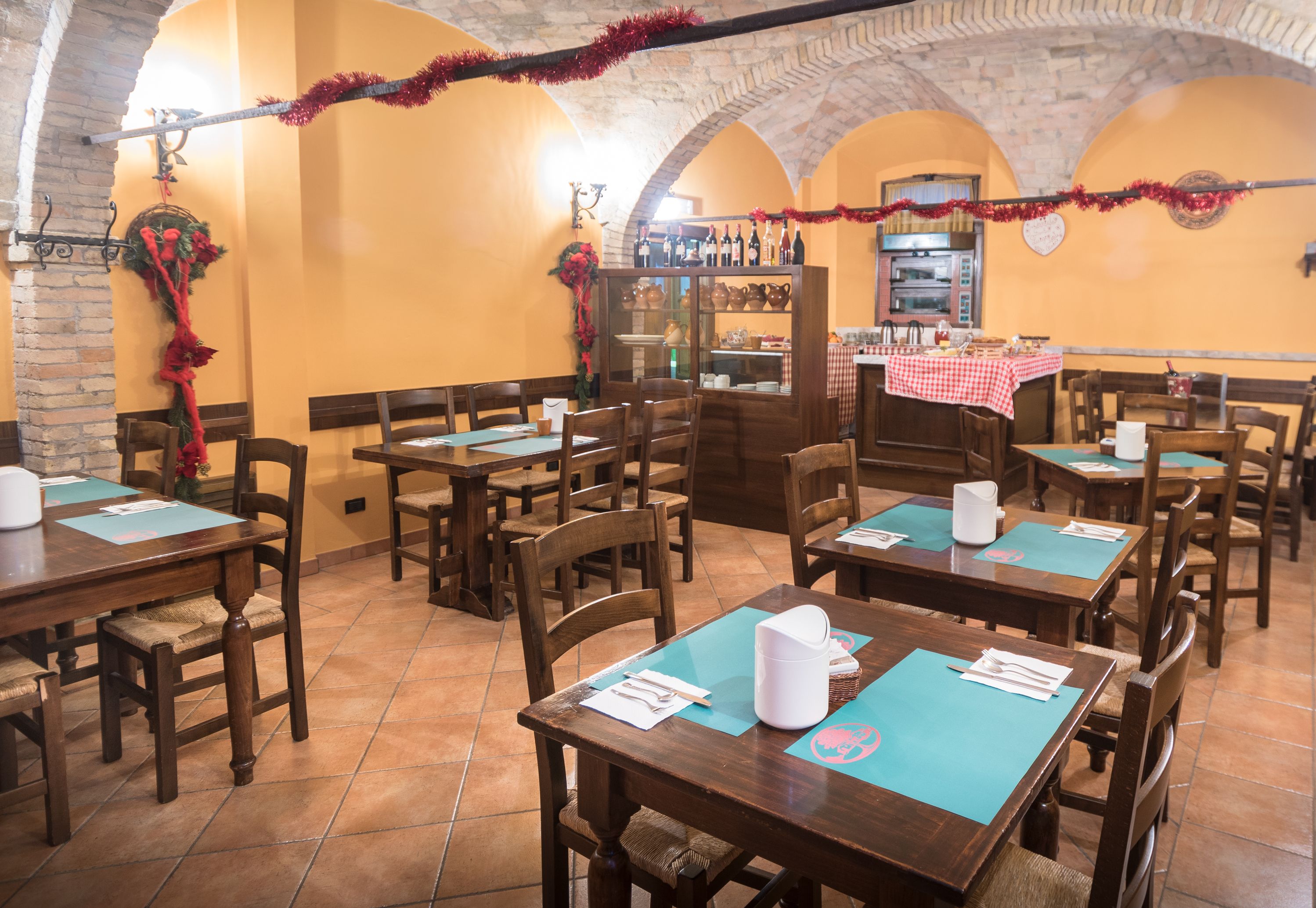 Un restaurante con mesas y sillas de madera, pared de ladrillo y piso de baldosas.
