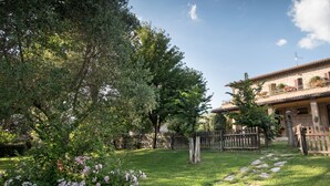 A garden with a stone pathway leading to a building with a balcony. - Agriturismo Il Giardino dei Ciliegi (Assisi)