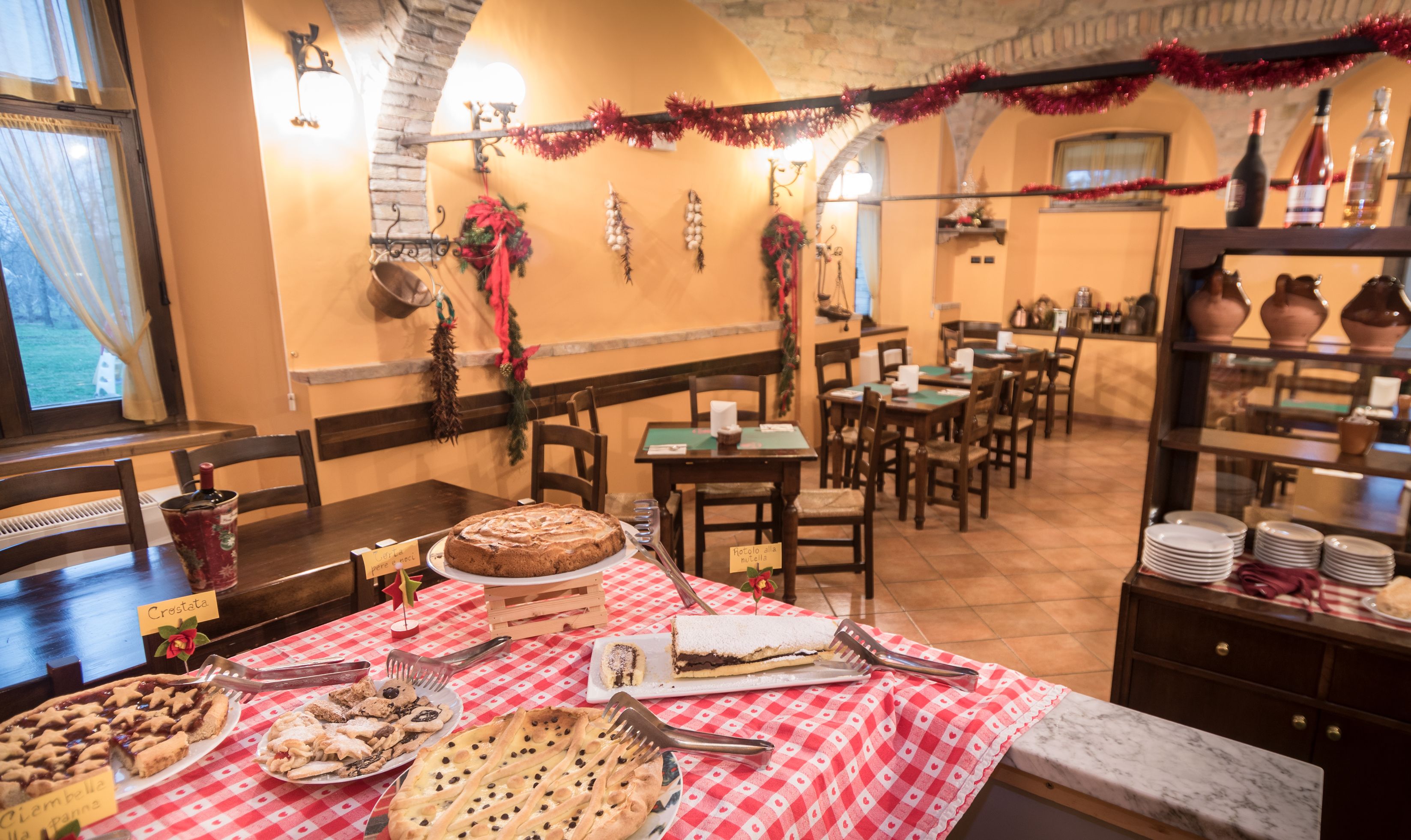 Ein Restaurant mit karierter Tischdecke, einer Auswahl an Desserts und rustikalem Ambiente mit Steinwänden und Holzmöbeln.