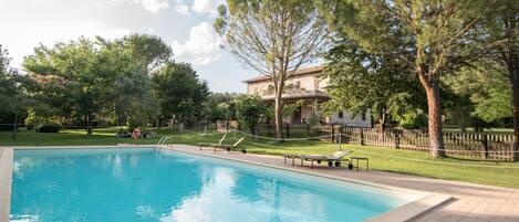 Una piscina al aire libre de temporada, sillones reclinables de piscina