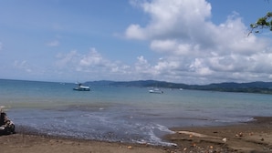 A beach with boats in the water and mountains in the background. - El Tesoro de Sir Hotel (Drake Bay)