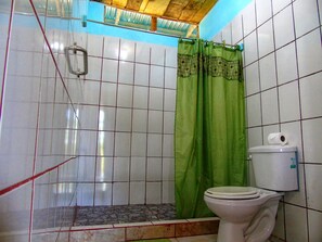 Un baño con inodoro, cortina de ducha verde y paredes de azulejos.
