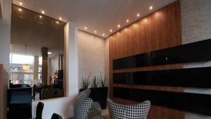 Un interior moderno con un espejo grande, sillas con estampado blanco y negro y una pared de acento de madera.
