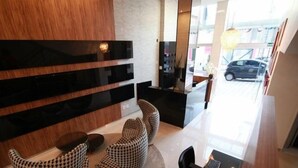 Un interior moderno con una pared de madera, estantes negros y una zona de estar con sillones estampados.