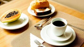 A table with a half-cut papaya, a sandwich, and a cup of coffee.