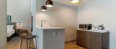 Una cocina moderna con una isla central, taburetes de bar, microondas y un lavamanos.
