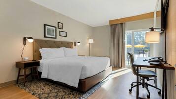 Una habitación de hotel con cama, mesitas de noche, escritorio y una silla.