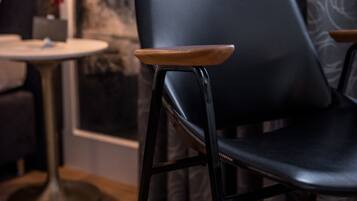 Un intérieur moderne avec un fauteuil en cuir noir, une table ronde et des rideaux à motifs.