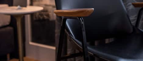 A modern interior with a black leather chair, a round table, and patterned curtains.