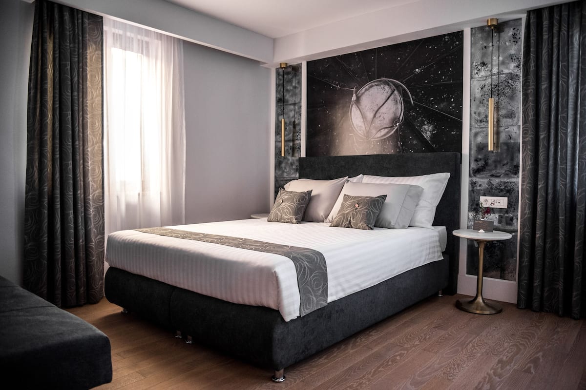 A modern bedroom with a large bed, a small round table, and a wall mural.
