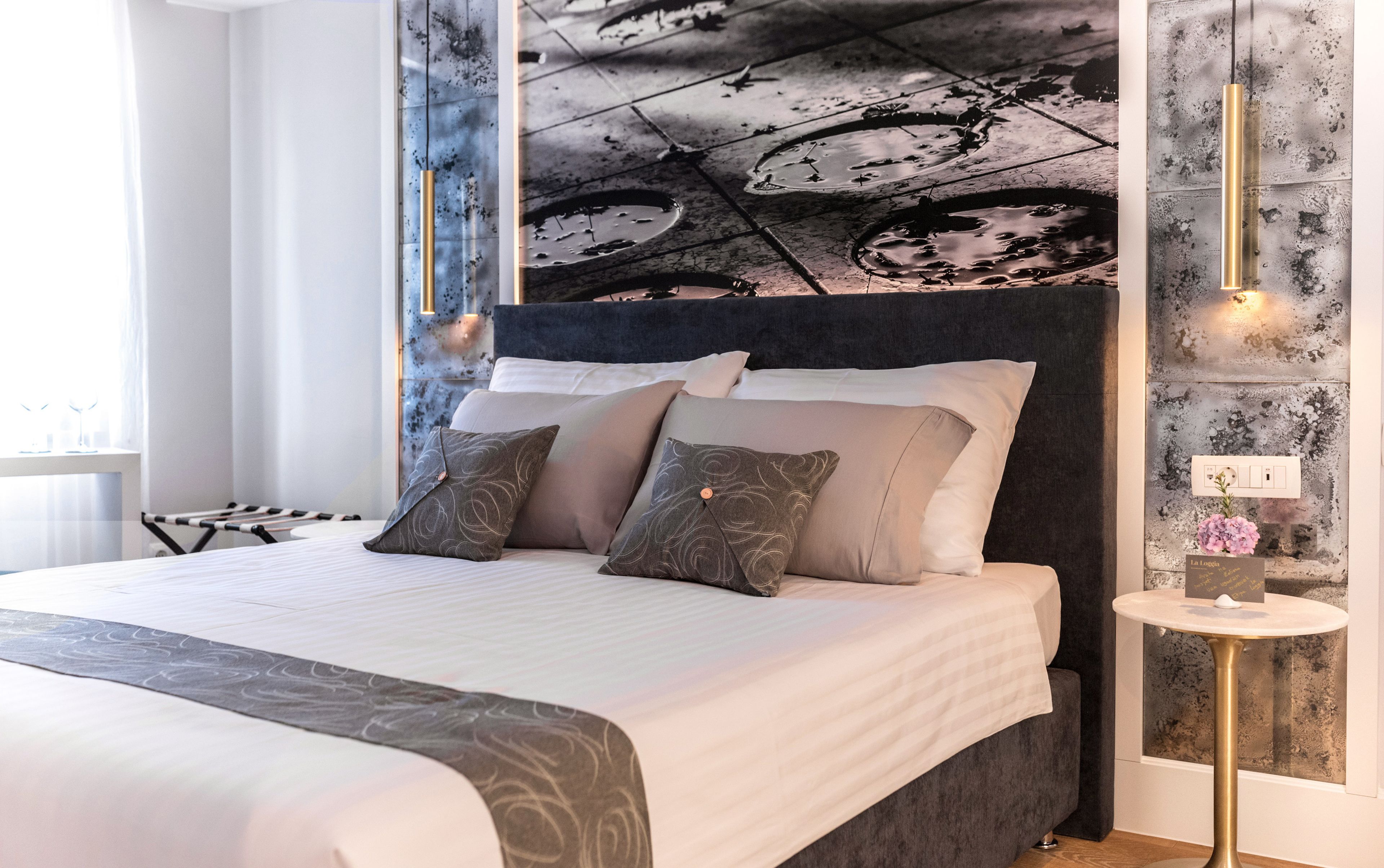 A modern bedroom with a large bed, a dark headboard, and a unique wall mural.