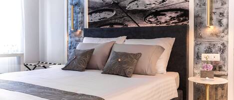 Un dormitorio moderno con una cama grande, cabecera oscura y un mural único en la pared.