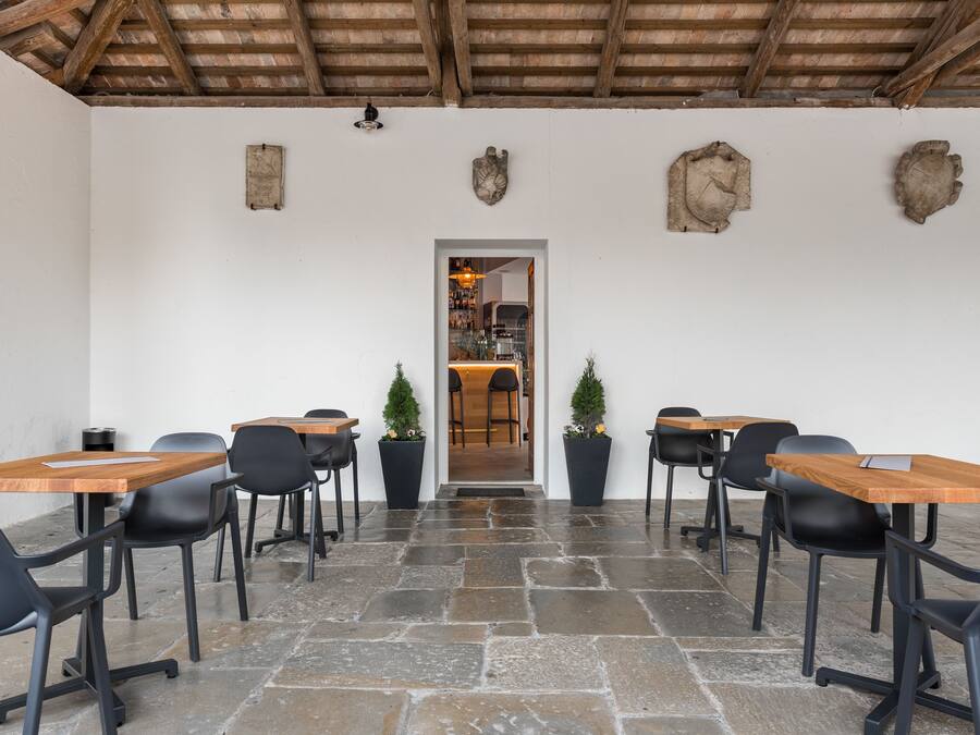 A conference room with stone flooring, wooden tables, and black chairs.