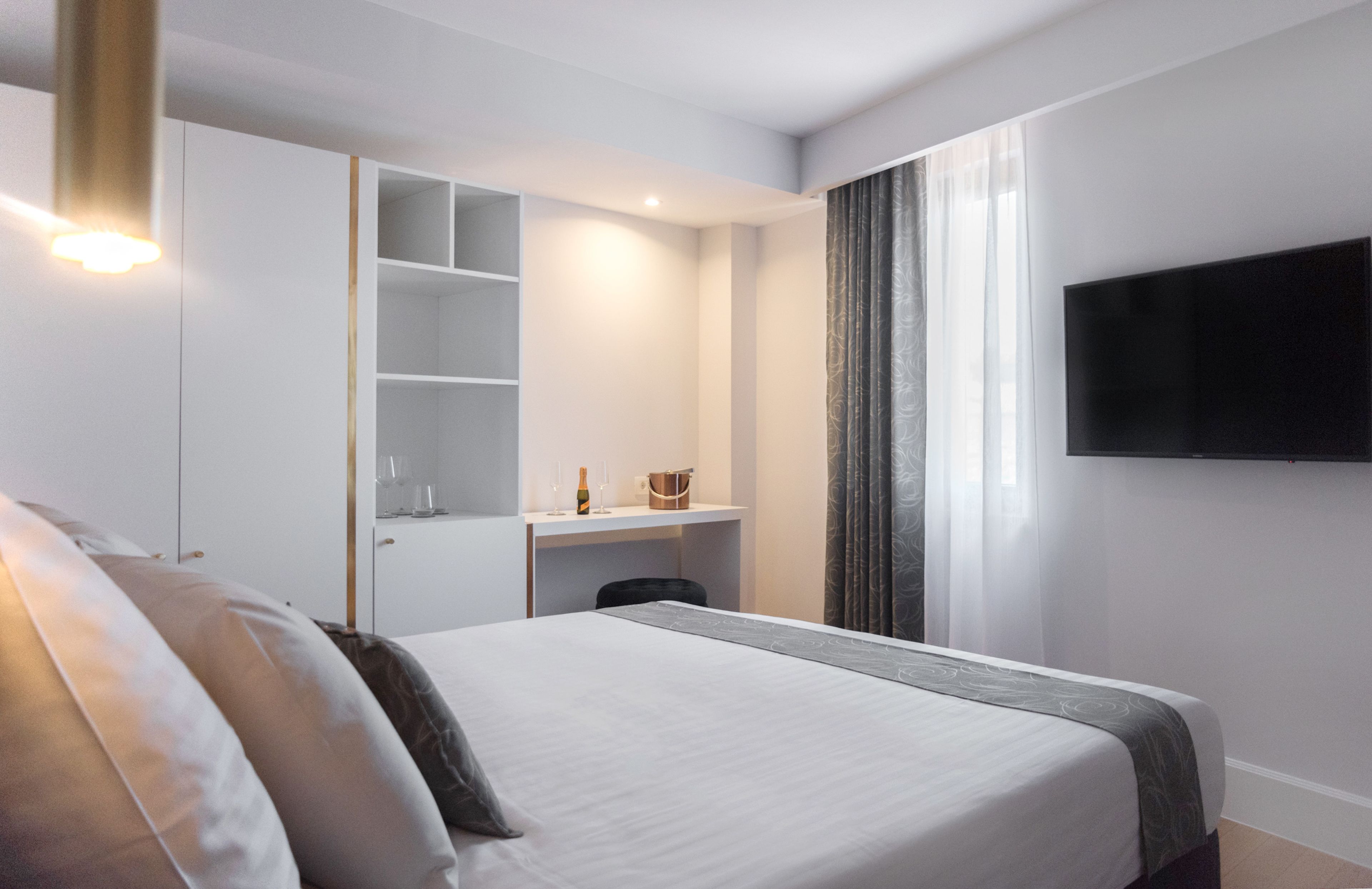 Une chambre d’hôtel équipée d’un lit, d’un bureau, d’une télévision et d’un mini-bar.