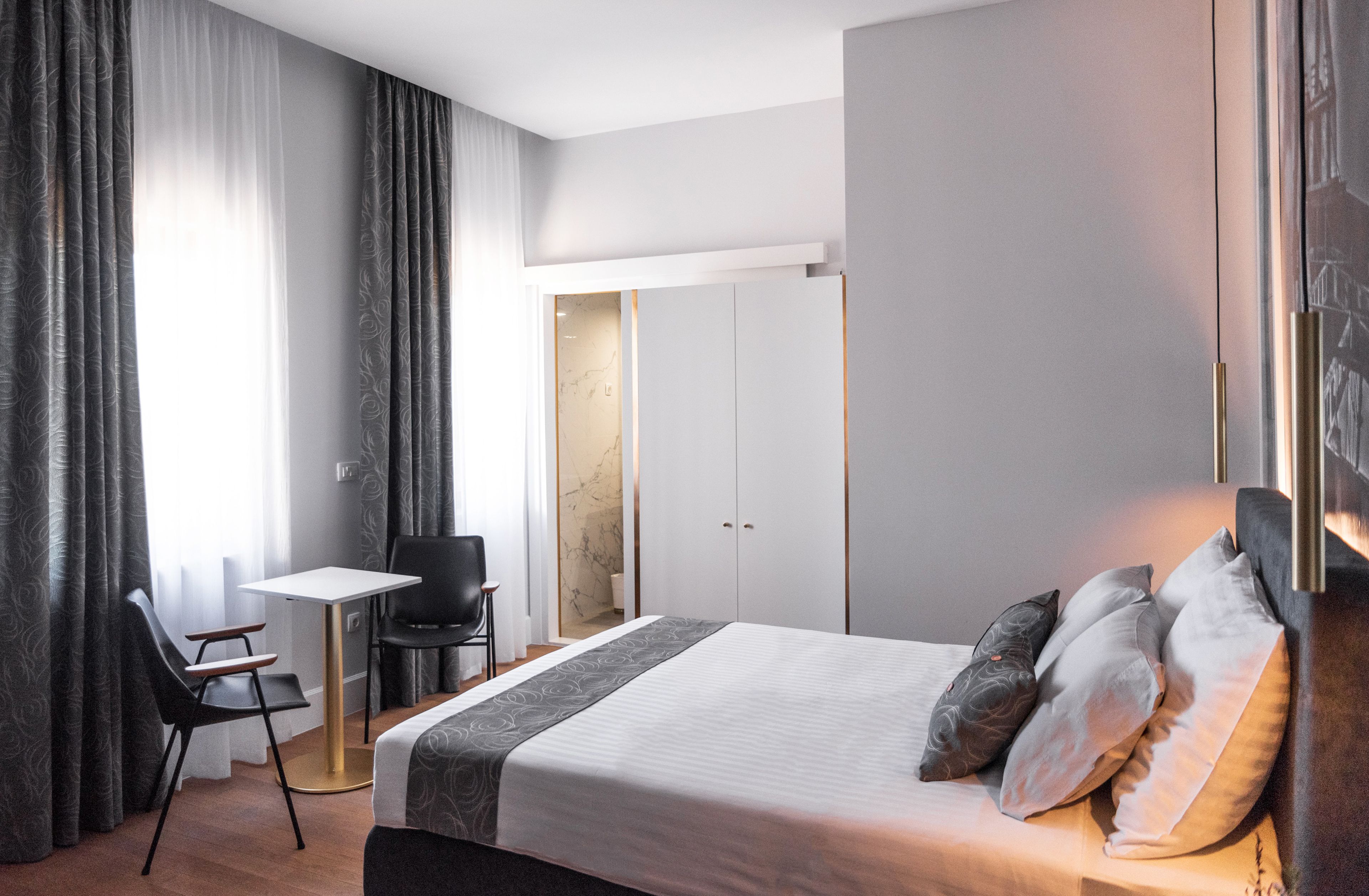Quarto de hotel moderno com uma cama grande, uma mesa e uma cadeira.