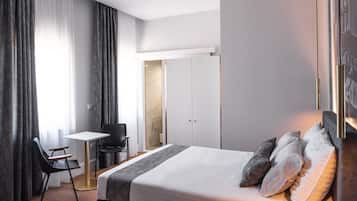 Una camera d'albergo moderna con un letto grande, una scrivania e una sedia.