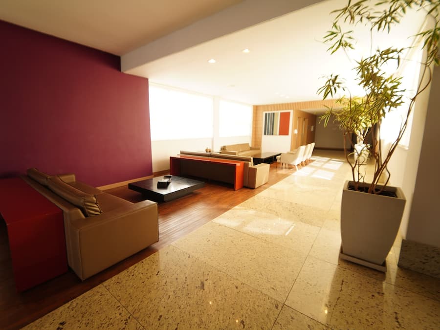 Una sala de estar moderna con una pared de acento roja, un sofá seccional, una mesa de centro y una planta en maceta.