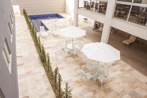 Um terraço no telhado com área de estar ao ar livre, piscina e vista do interior do edifício.