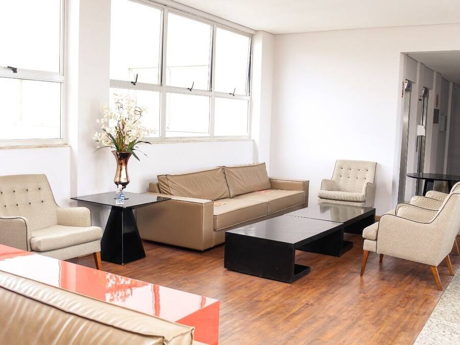 Una sala de estar moderna con un sofá, dos sillones, una mesa de centro y un jarrón con flores.