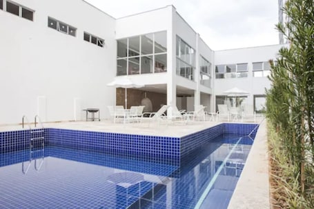 Una piscina al aire libre, sombrillas, sillones reclinables de piscina