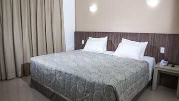 Una habitación de hotel con una cama grande, una mesita de noche con teléfono y una cortina en la ventana.