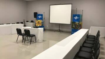 A conference room with a long table, chairs, a projector screen, and a whiteboard.