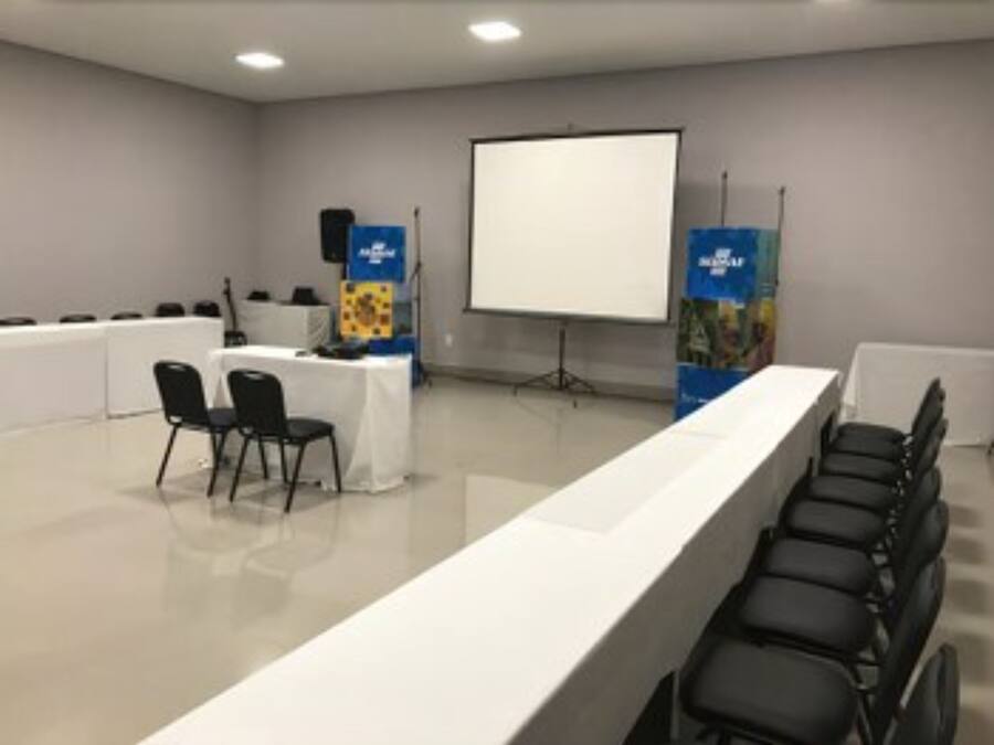 A conference room with a long table, chairs, a projector screen, and a whiteboard.