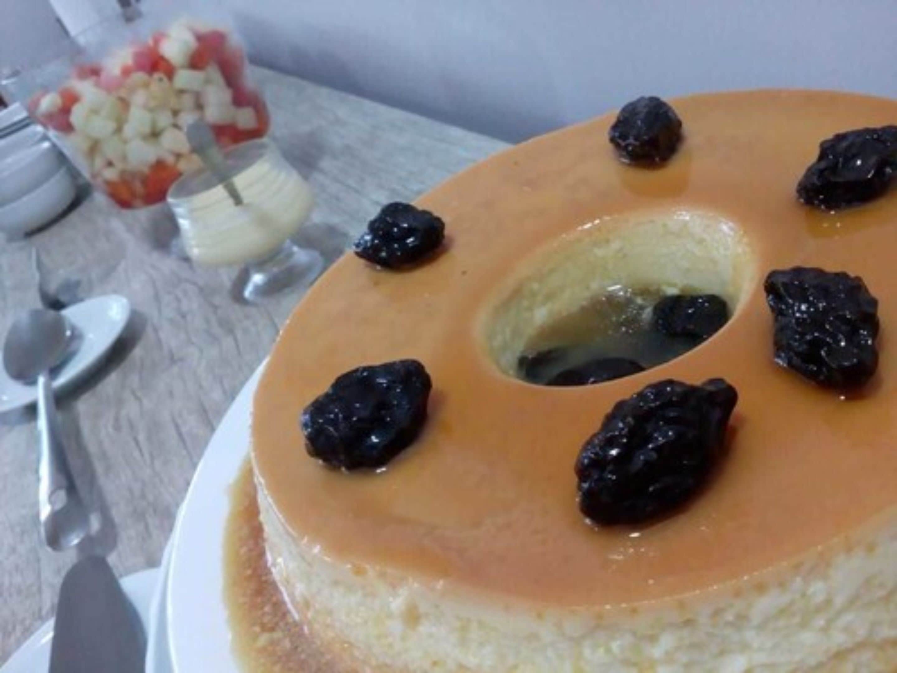 A dessert with a caramelized top, a hole in the center, and raisins around it.