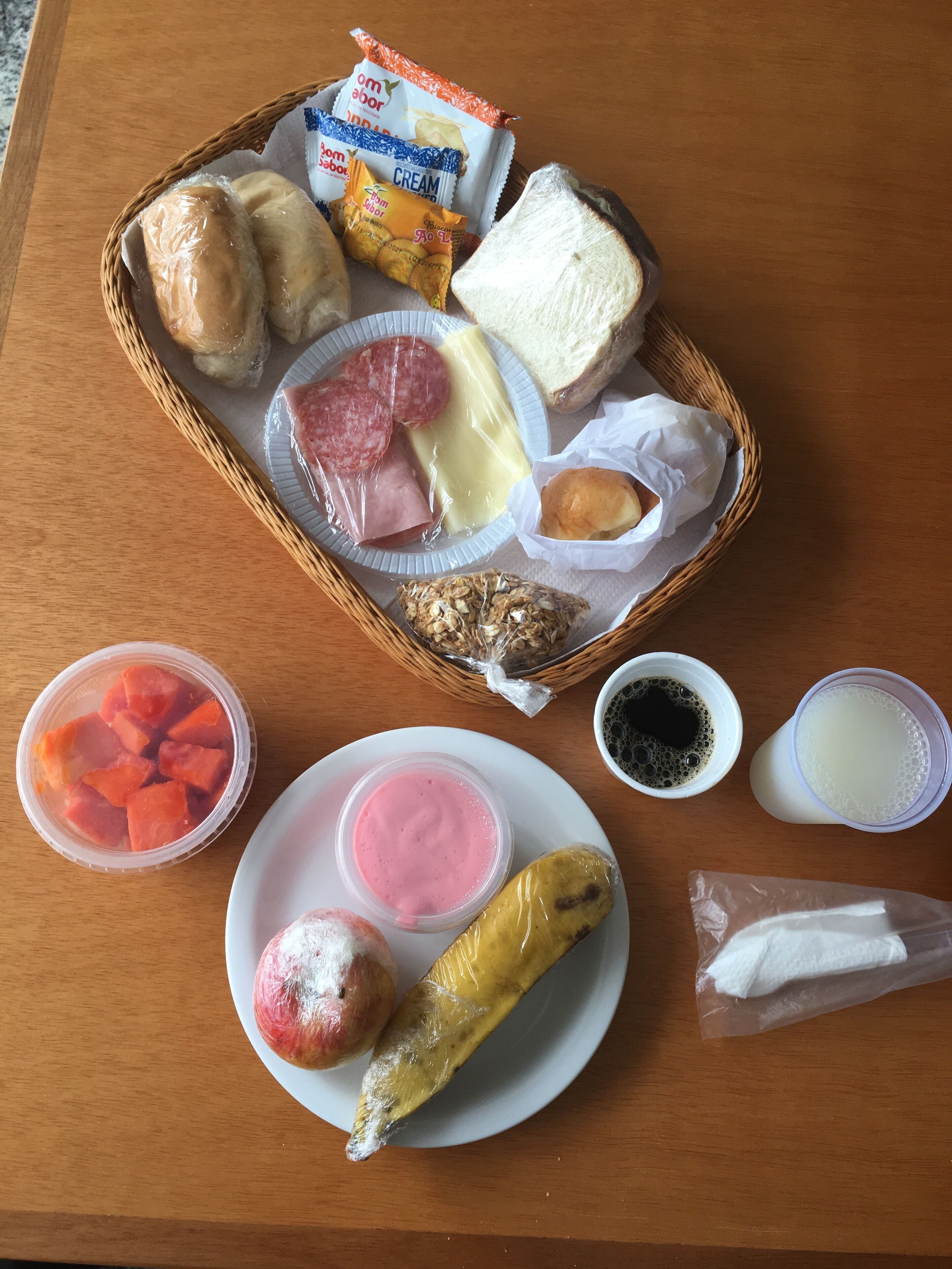 Una comida con pan, queso, jamón y una banana sobre una mesa de madera.