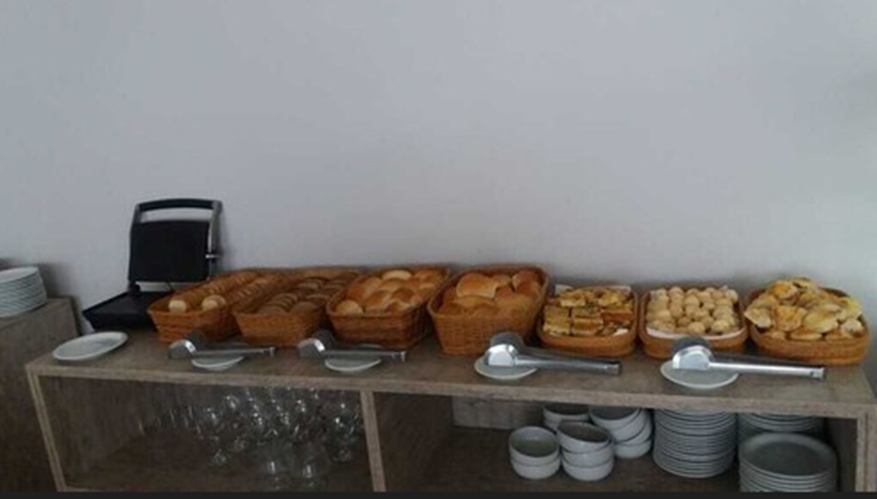 A buffet table with various baked goods and utensils.