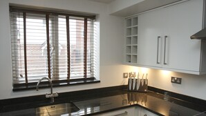 A modern kitchen with a black countertop, stainless steel sink, and white cabinets. - 2 Bed Apt in Chorleywood Near Station (Rickmansworth)