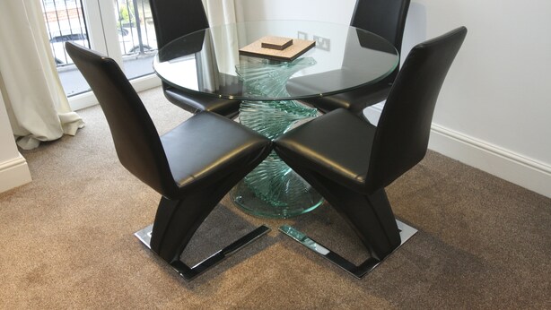 A glass-top table with four black chairs, a small glass table with a book, and a view of the street outside. - 2 Bed Apt in Chorleywood Near Station (Rickmansworth)